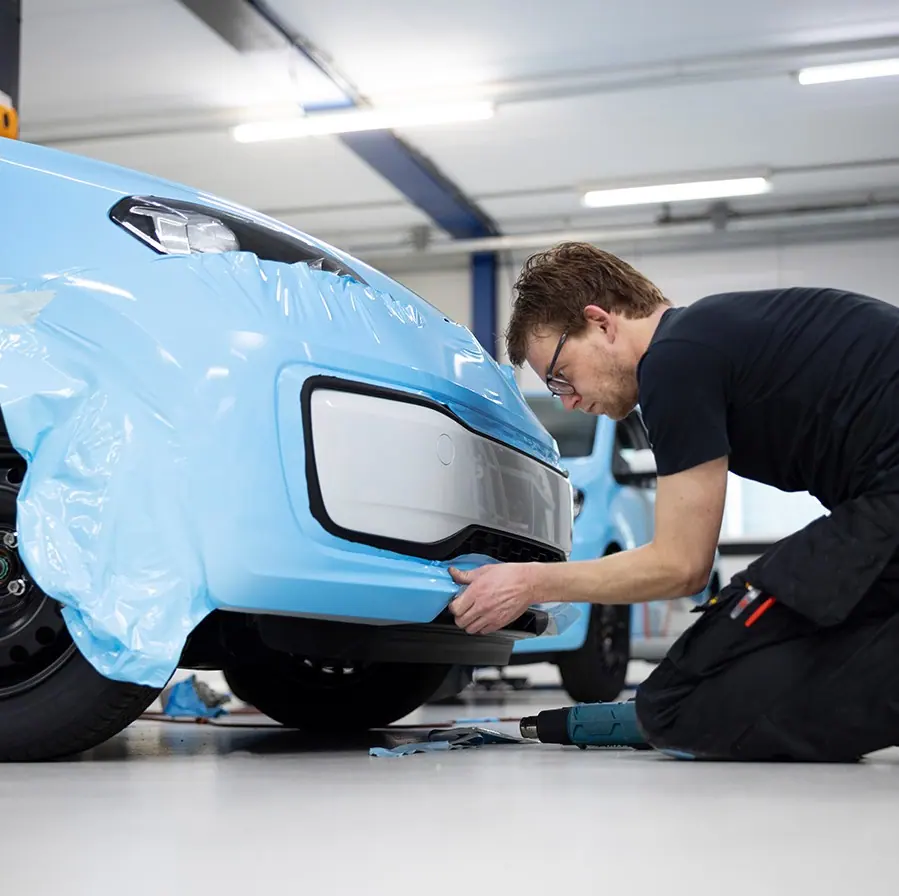 ProFleet Graphics installer laying cast vinyl over a vehicle bumper in the shop